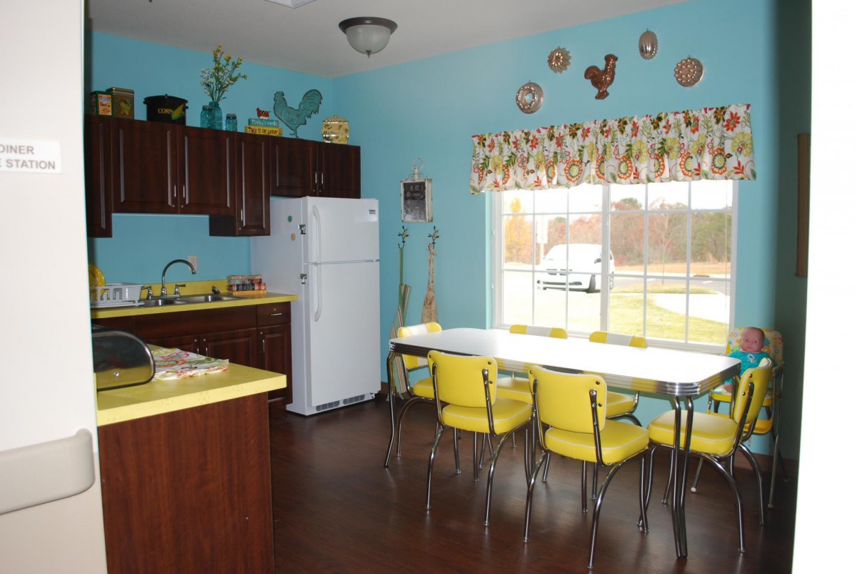 A retro-style kitchen with bright yellow chairs, blue walls, and vintage decorations.