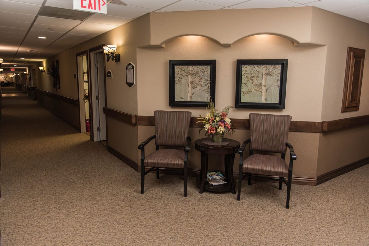A hallway with two chairs and framed artwork on the wall, creating a cozy waiting area.
