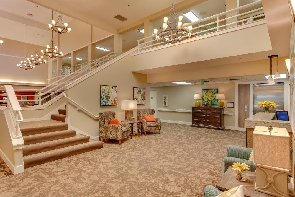 A spacious and elegantly decorated lobby area with comfortable seating, chandeliers, and a staircase.