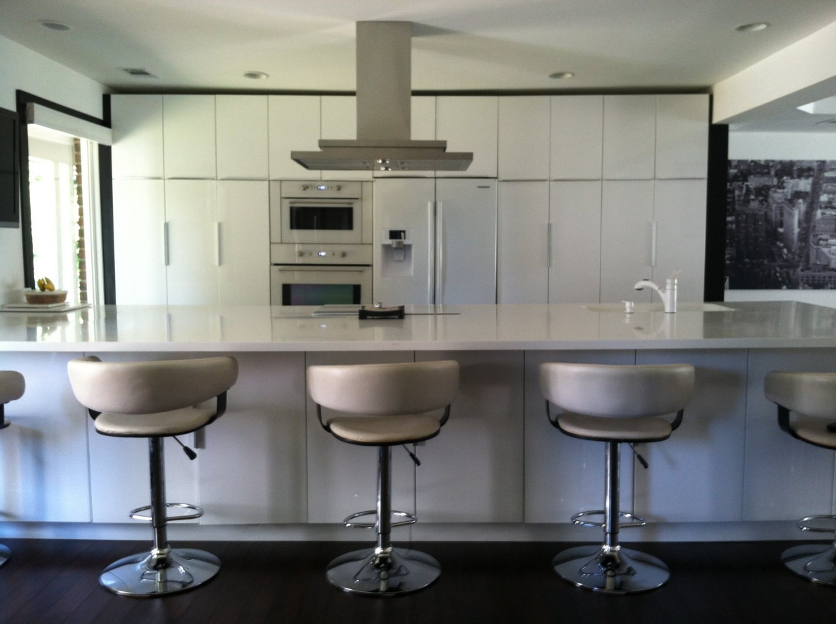A modern kitchen with a sleek design, featuring a spacious counter and stylish bar stools.