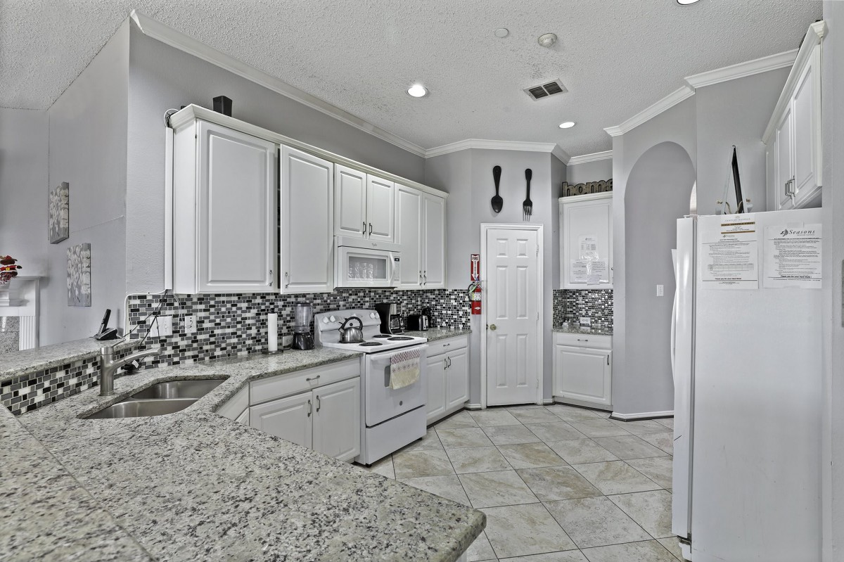A modern kitchen featuring white cabinets, granite countertops, and a stylish backsplash.