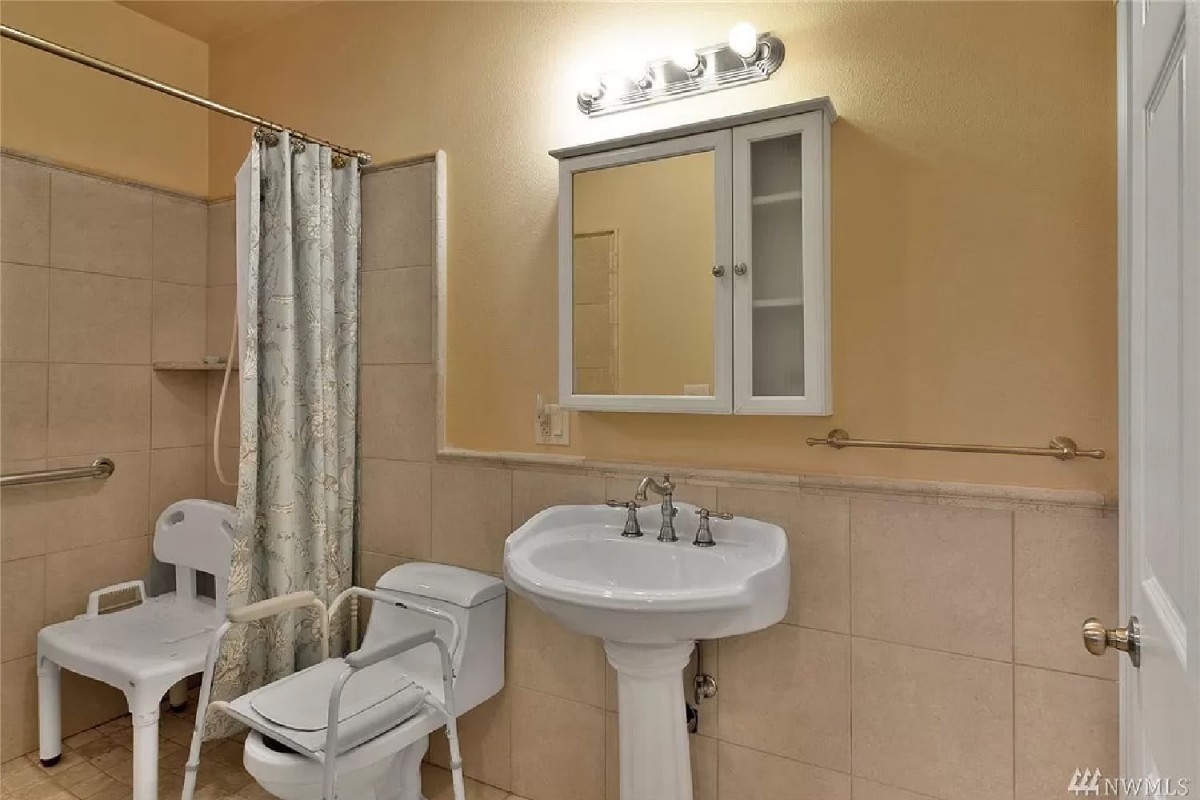 A small bathroom with a pedestal sink, wall-mounted cabinet, and shower curtain.