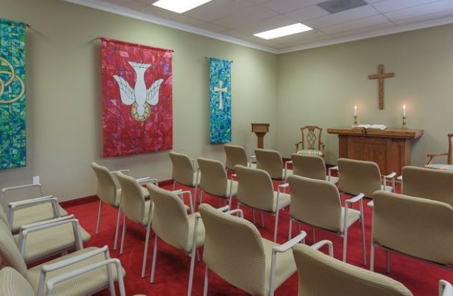 A small chapel interior with rows of chairs facing an altar, adorned with religious banners.