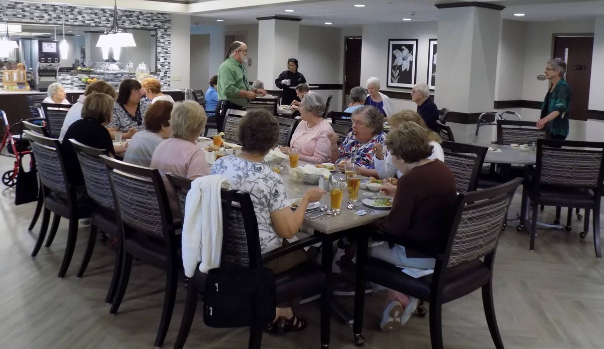 A group of seniors enjoy a meal together in a restaurant setting.