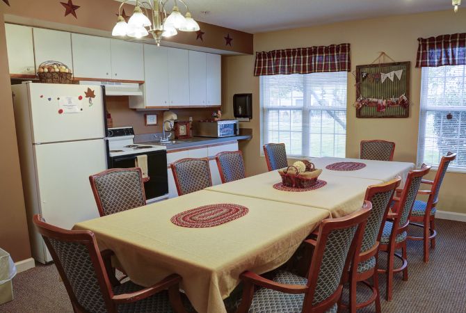 A cozy kitchen with a dining table set for a meal, featuring chairs and a window view.
