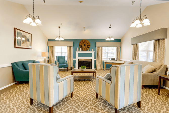 A cozy living room with a fireplace, featuring striped armchairs and decorative elements.