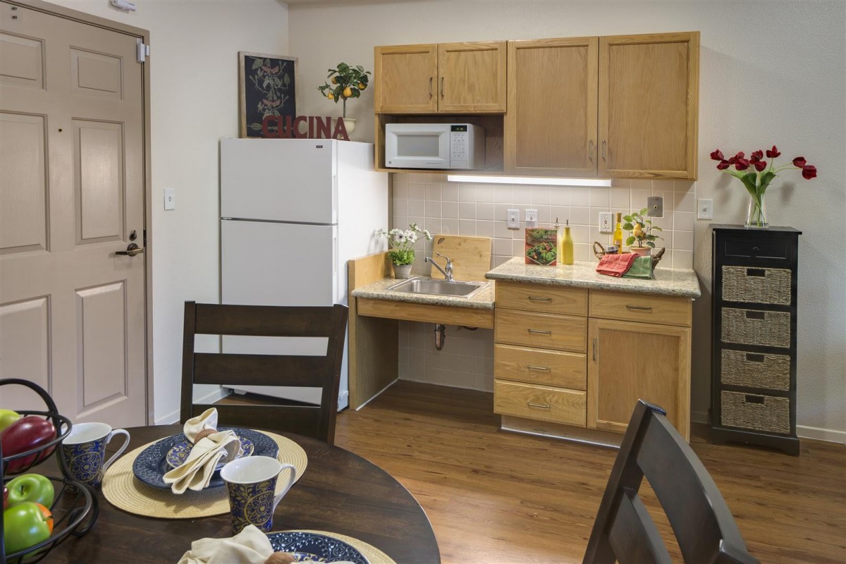 A cozy kitchen and dining area with wooden cabinets, a refrigerator, and a table set for dining.