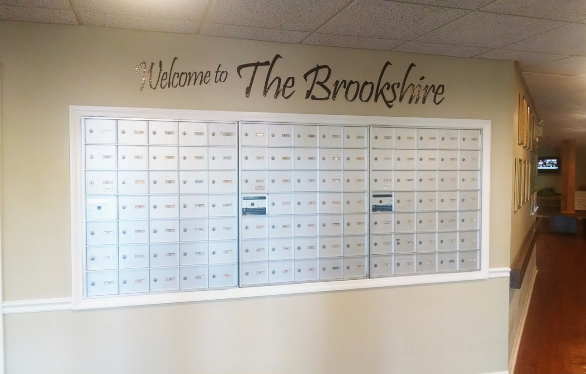 A wall of mailboxes with a 'Welcome to The Brookshire' sign above them.