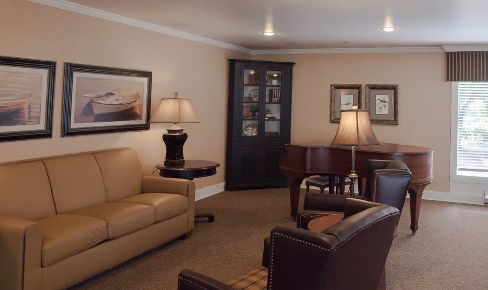 Cozy living room with a piano, sofas, armchairs, and elegant decor.