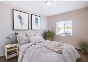 A cozy, minimalist bedroom with a neatly made bed, wall art, and a potted plant by the window.