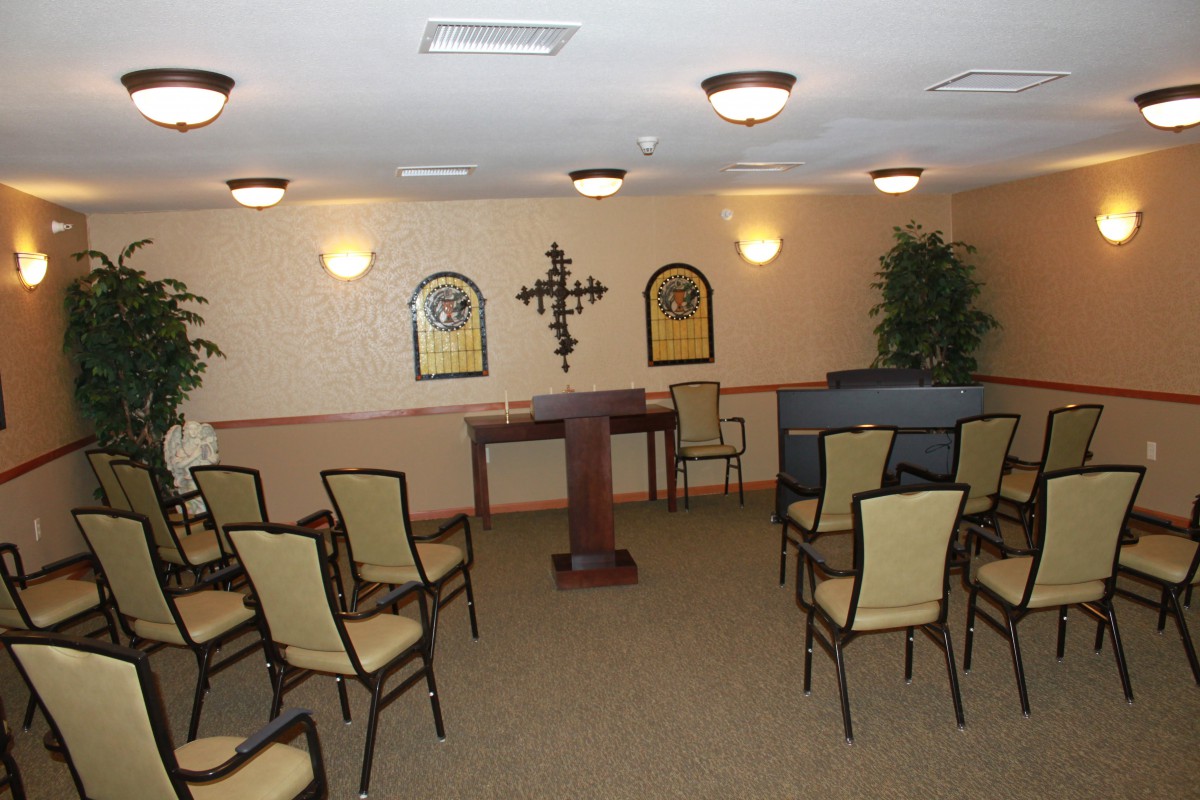 A small chapel or meeting room with arranged chairs, a lectern, and wall decorations.