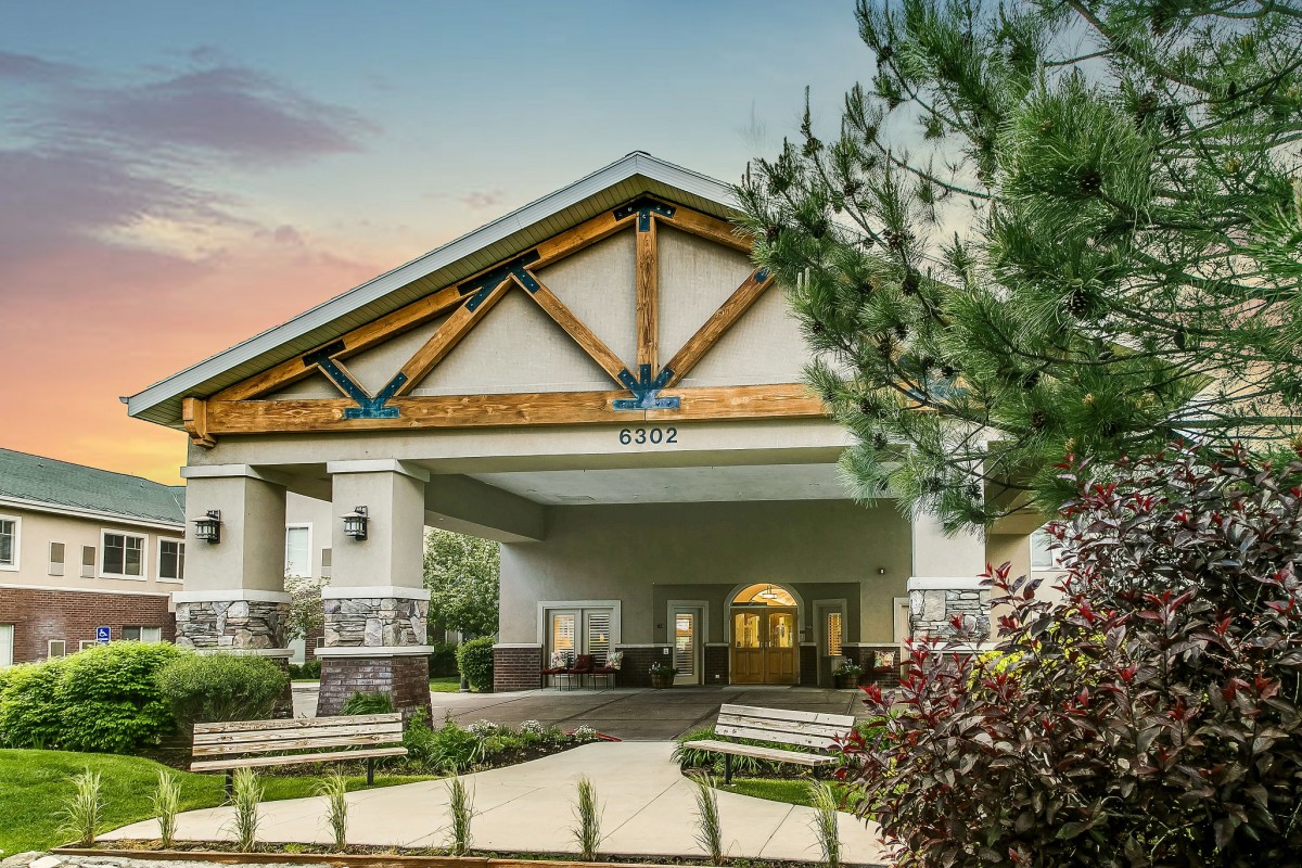 A modern building entrance surrounded by trees and landscaping.