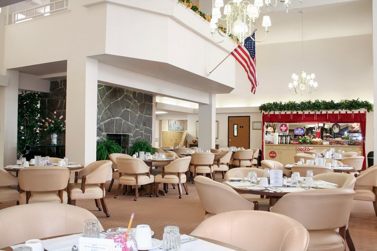 A spacious dining hall with elegant decor, featuring a chandelier and an American flag.