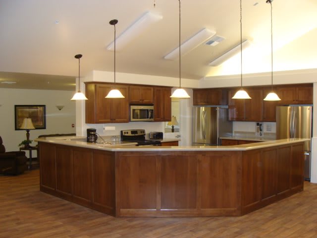 A modern kitchen with wooden cabinets, an island, and stainless steel appliances.