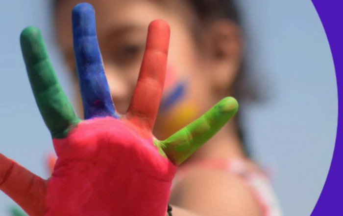 A child with a brightly painted hand showing creativity and fun.