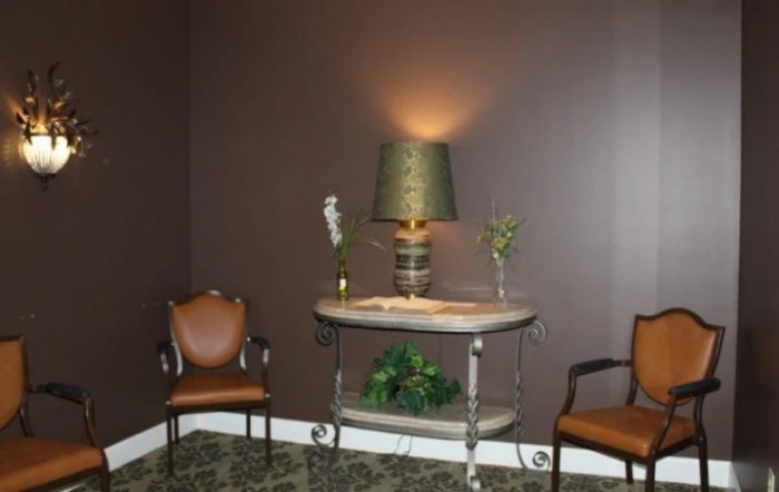 A cozy interior setting featuring a lamp on a table, flanked by two chairs and decorated with plants.