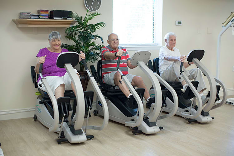 A group of seniors exercising on stationary bikes in a gym setting.