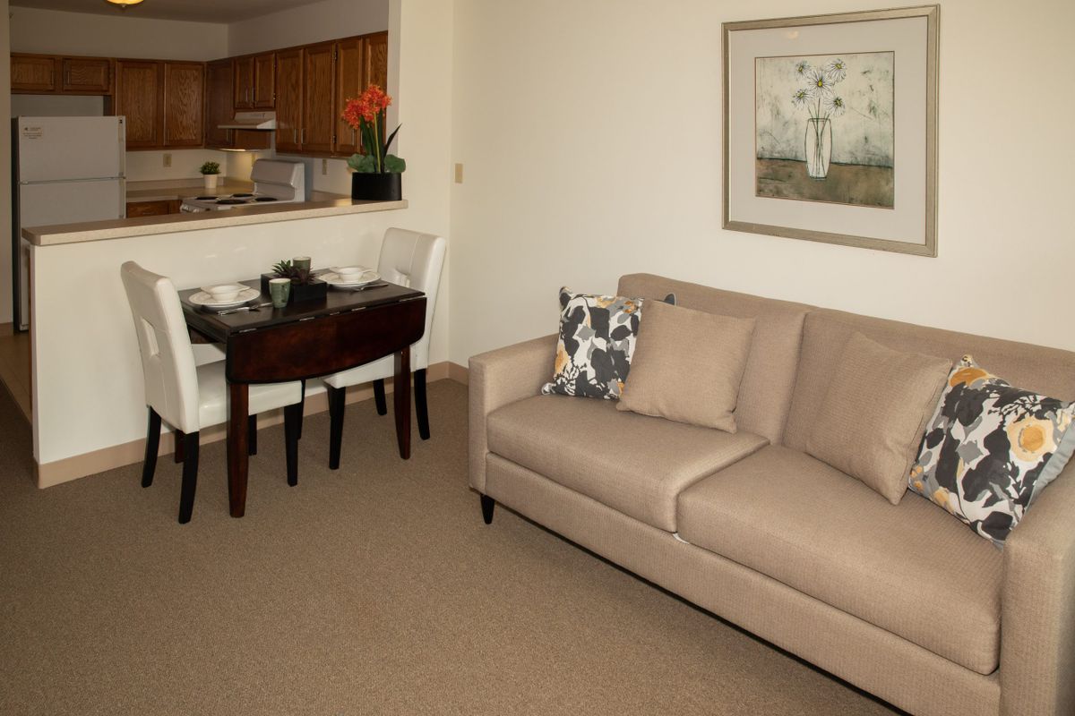 A cozy living room with a beige sofa and dining area in view.