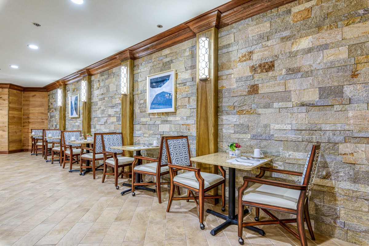 A cozy cafe interior with stone walls, wooden tables, and comfortable chairs.