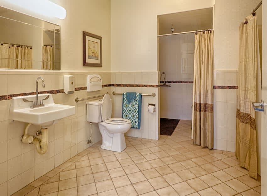 A spacious bathroom with a sink, toilet, and shower area featuring tiled flooring.