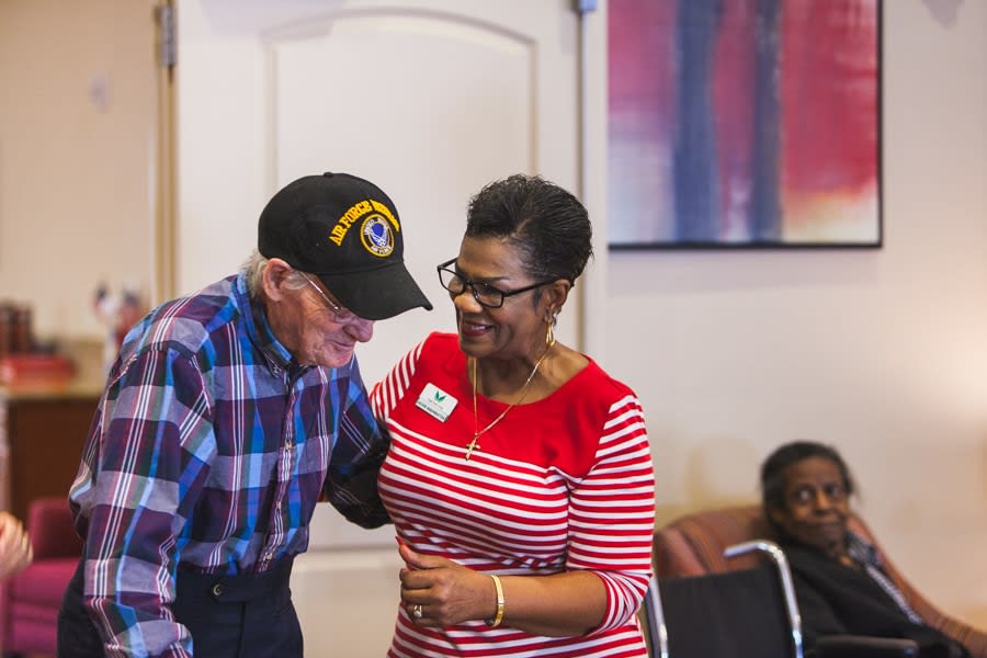 A woman assists an elderly man, highlighting a moment of care and community support.