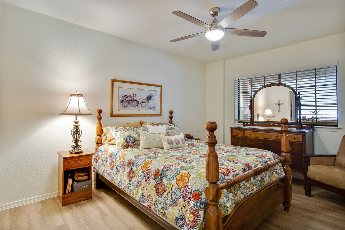 A cozy bedroom with a wooden bed frame, floral bedding, and warm lighting.