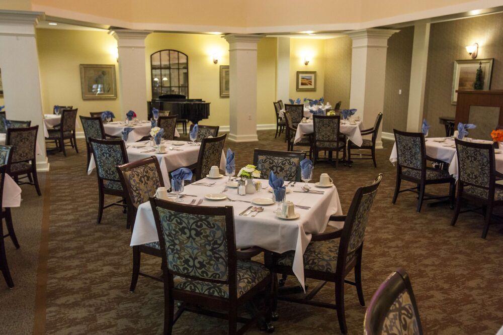 An elegant dining room with neatly arranged tables and chairs, set for a formal dinner.