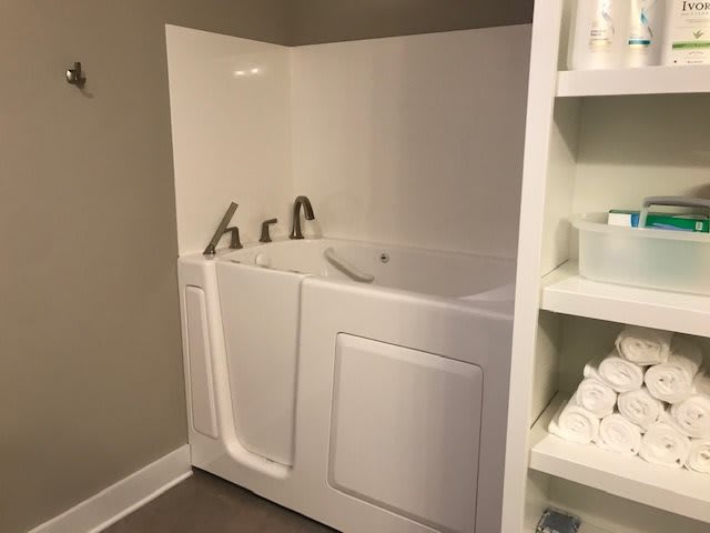 A walk-in tub designed for accessibility and safety in a bathroom setting.