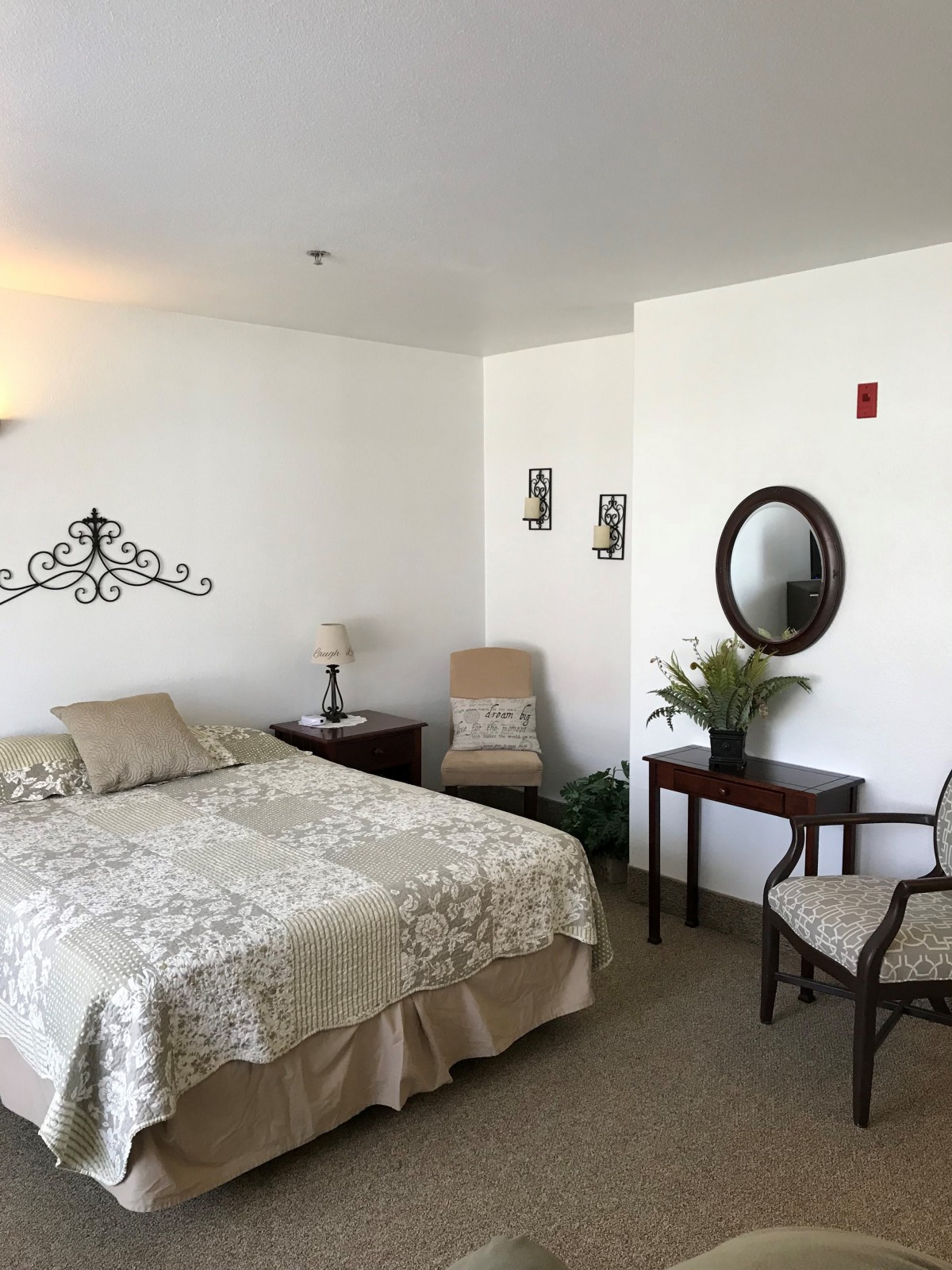A cozy bedroom with a double bed, side tables, chairs, and elegant wall decor.
