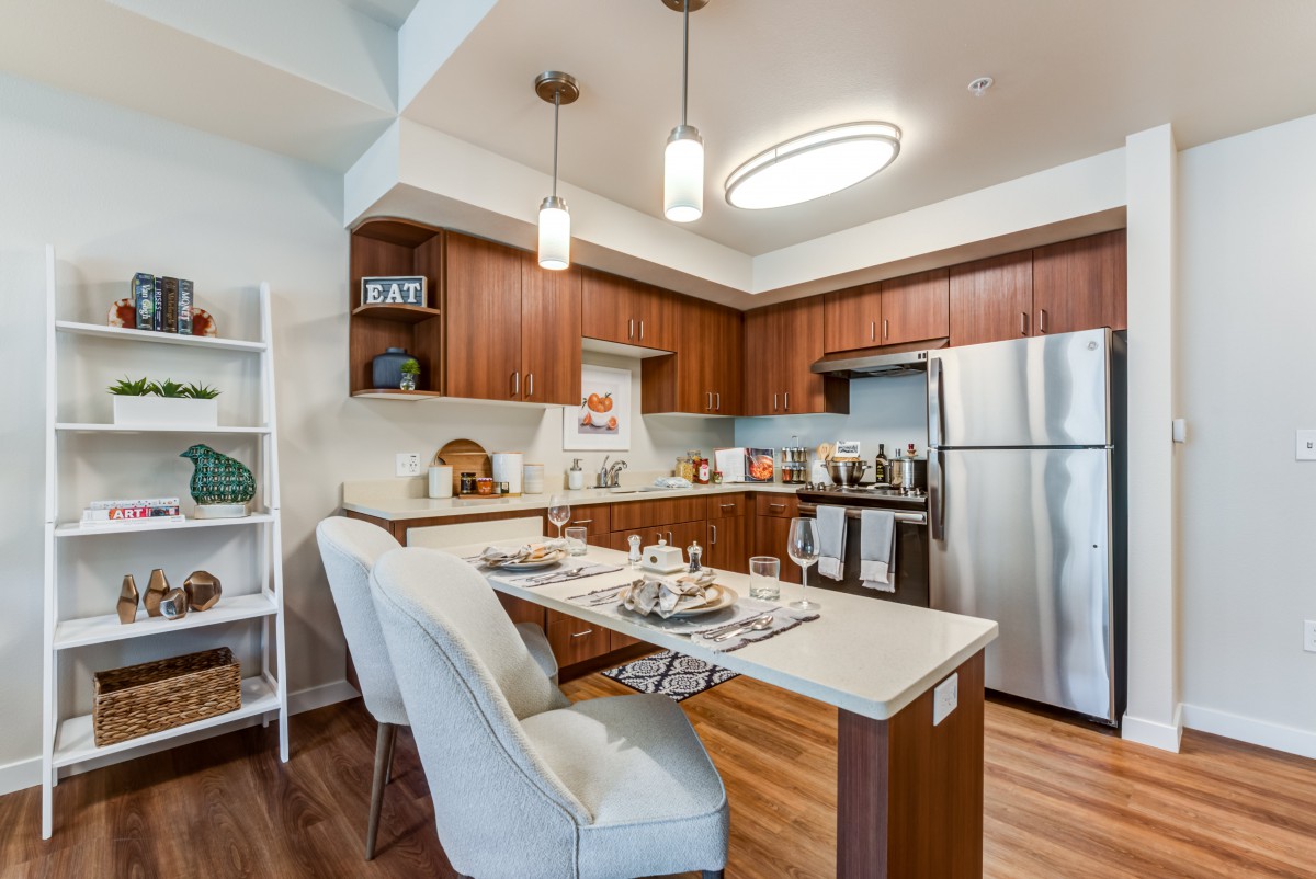 A modern kitchen with wooden cabinets, stainless steel appliances, and a cozy dining area.