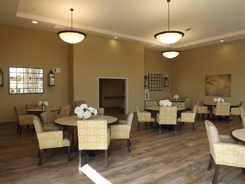 A well-lit dining area featuring several tables and chairs with decorative flowers.