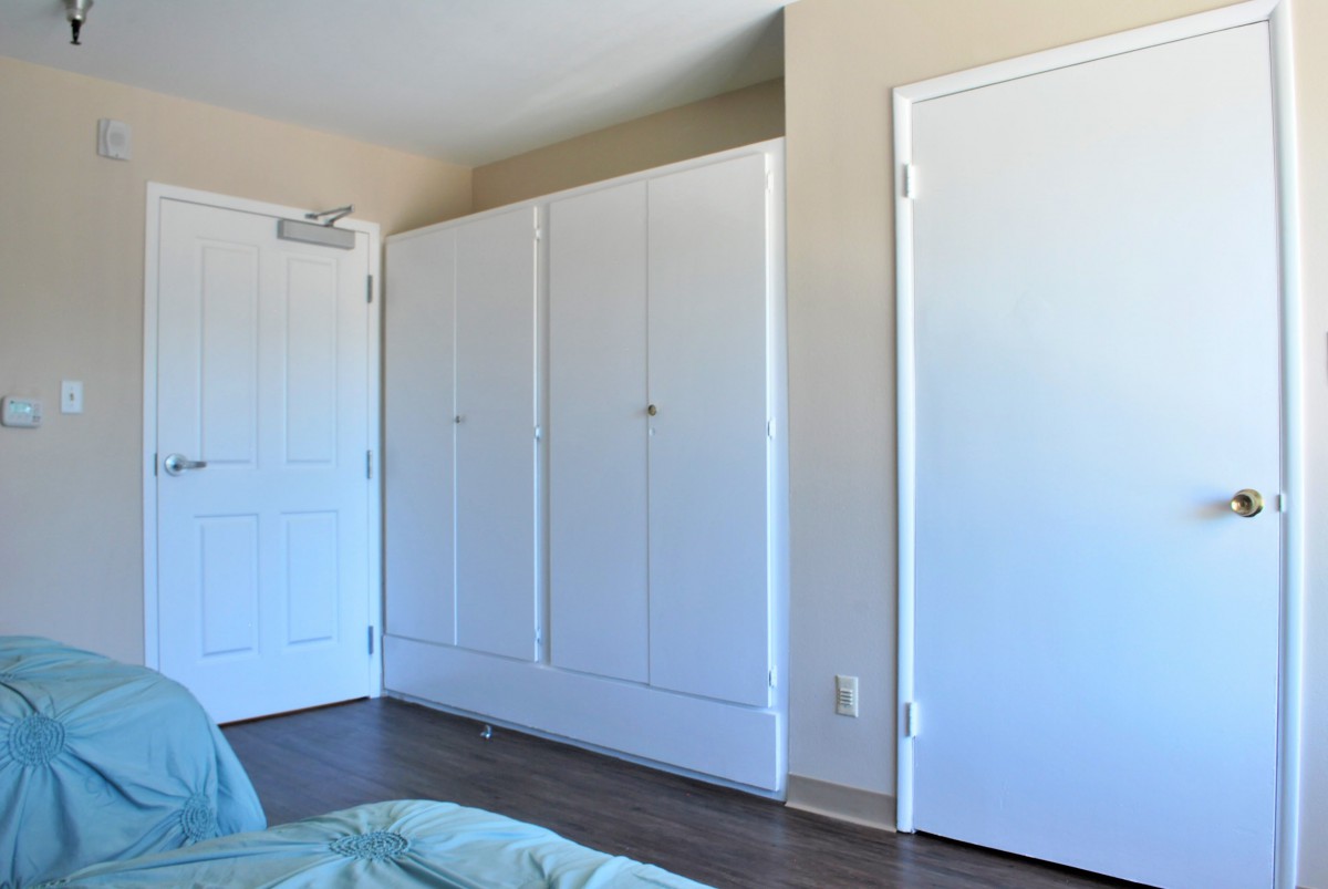 A minimalist bedroom interior with a large closet and white doors.