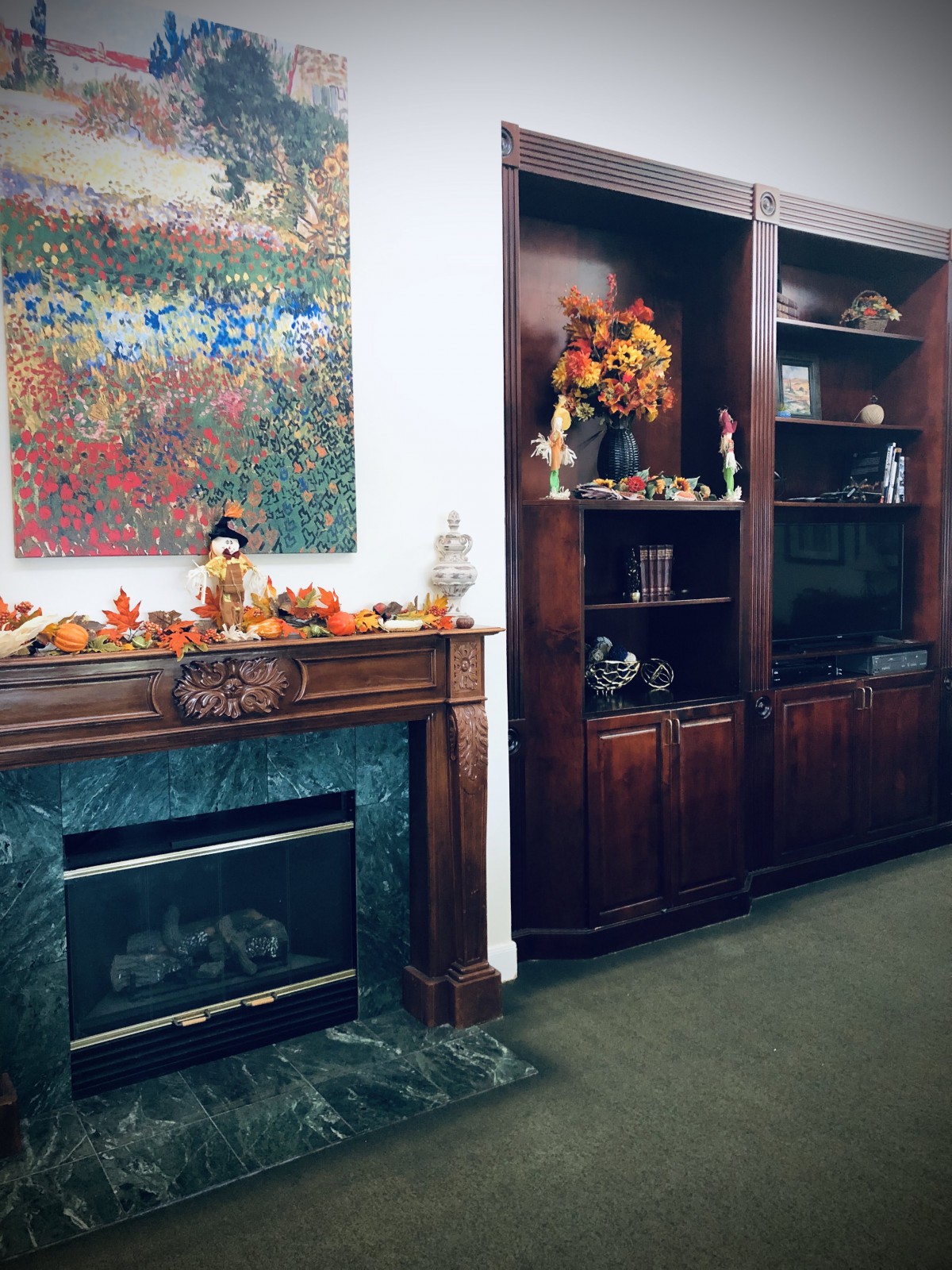An elegantly decorated room with a fireplace and bookshelves, featuring autumn-themed decor.