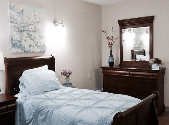 A neatly arranged bedroom with a single bed, dresser, and decorative elements.