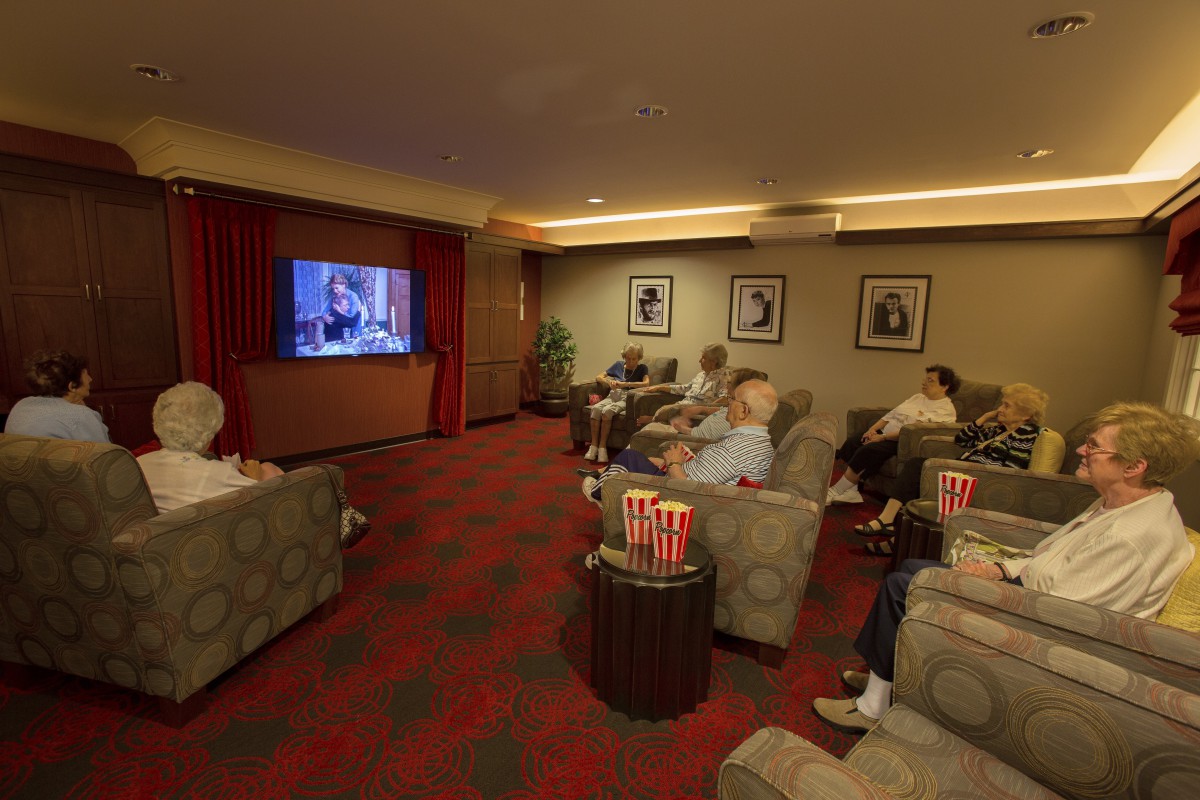 A cozy indoor movie theater with people relaxing and watching a film, enjoying popcorn.