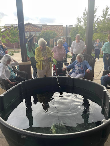 Seniors enjoying a tranquil moment by a water feature in an outdoor setting.