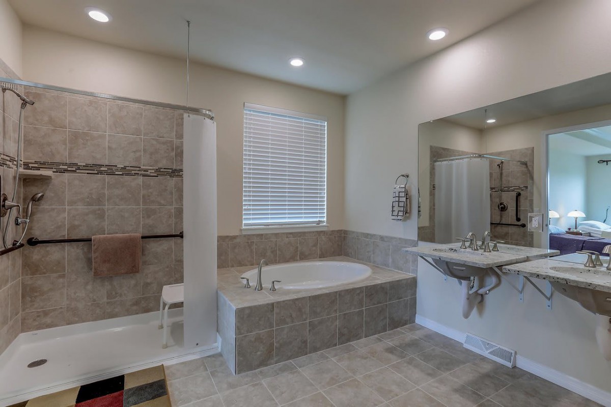 A modern bathroom featuring a shower, bathtub, and sink with a large mirror.