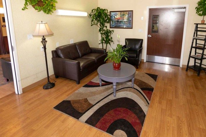 A cozy living room with a brown leather sofa, armchair, and a coffee table on a decorative rug.
