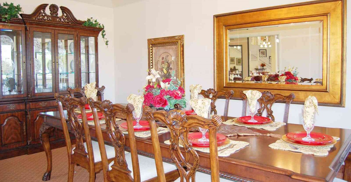 A dining room with an elegantly set table, featuring a floral centerpiece and decorative elements.