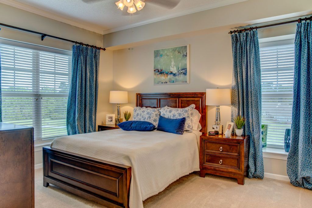 A cozy bedroom with stylish decor and a comfortable bed, featuring blue curtains and matching pillows.
