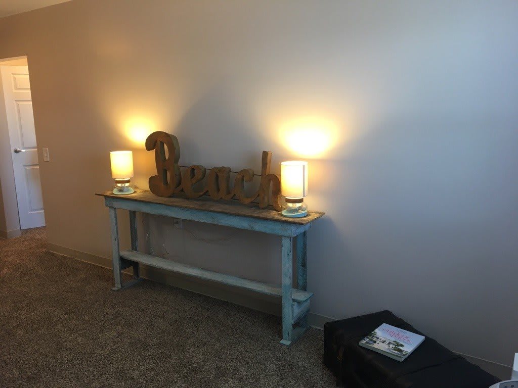 A stylish console table with two lamps and decorative items against a neutral wall.