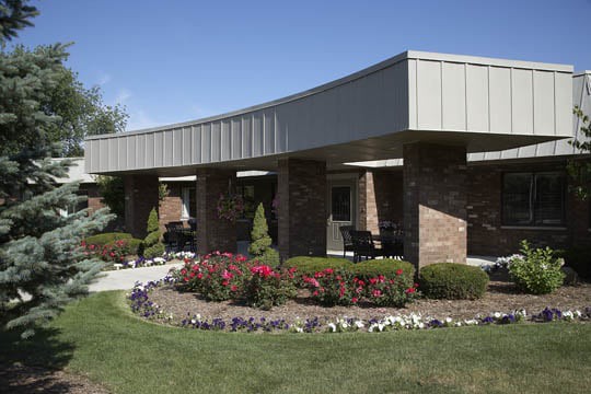 A modern building surrounded by a landscaped garden with vibrant flowers and greenery.