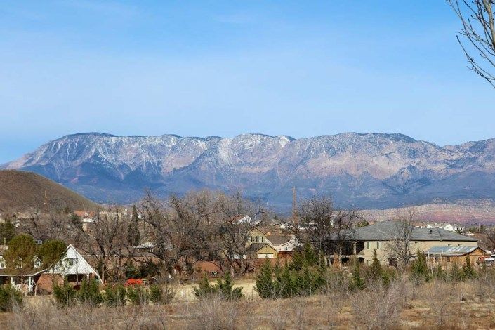 A serene rural landscape with a mountain range in the background under a clear blue sky.