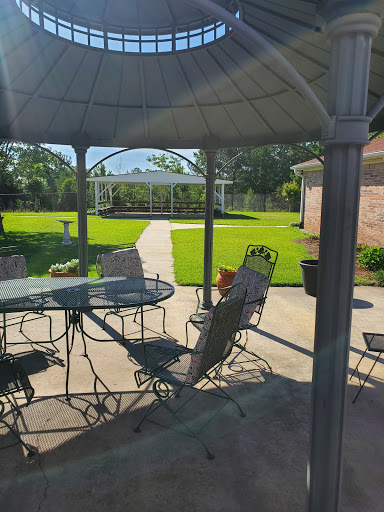 A serene patio setting featuring a gazebo, table, and chairs, perfect for enjoying a sunny day in the garden.