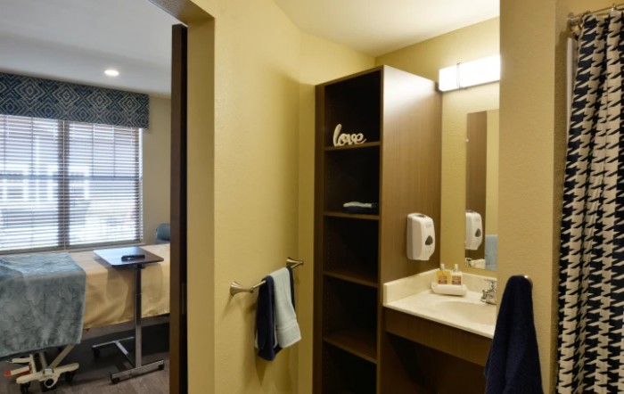 A modern bathroom with a mirror, sink, and shelving unit in a hotel room.
