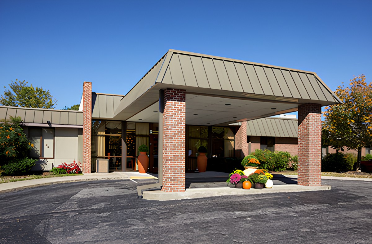 A commercial building entrance with a covered driveway and surrounding landscaping.