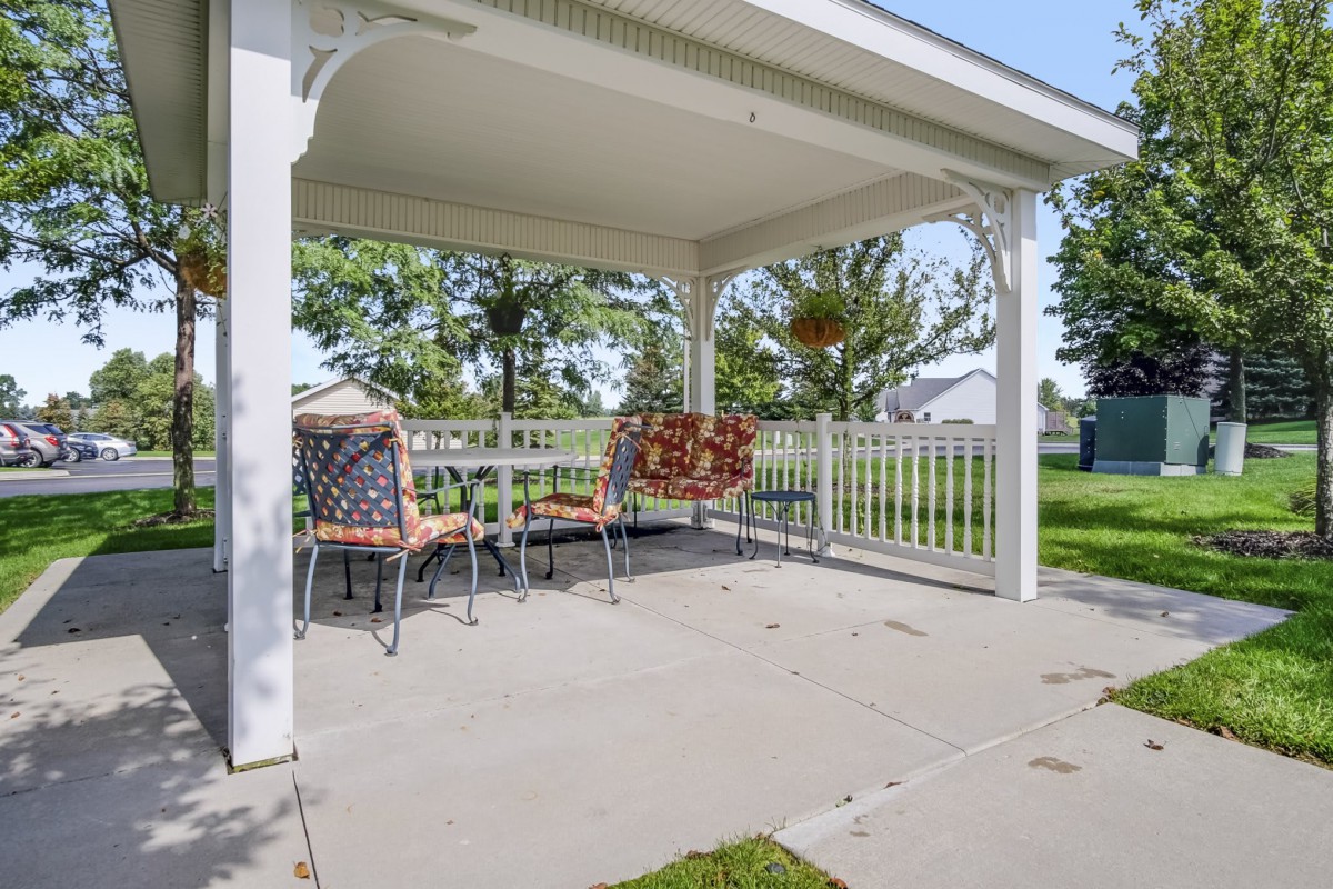 A cozy outdoor patio area with a gazebo covering, featuring a table and chairs for seating.