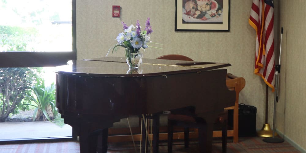 A grand piano adorned with a vase of flowers in a cozy interior setting.