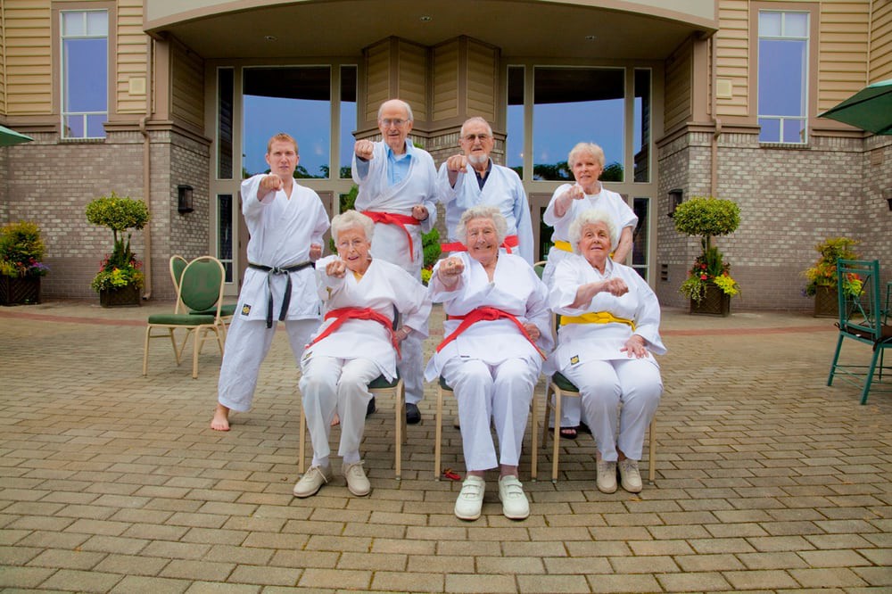 A group of seniors proudly showcase their karate skills in an outdoor setting.