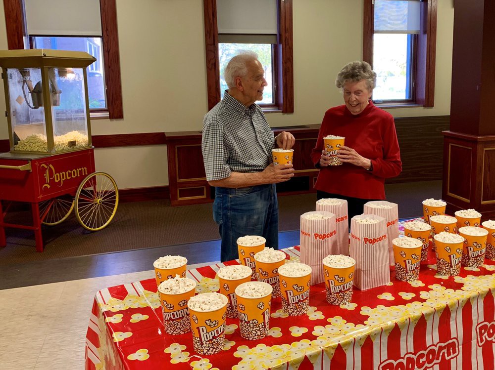 Two people enjoying popcorn at an indoor event.